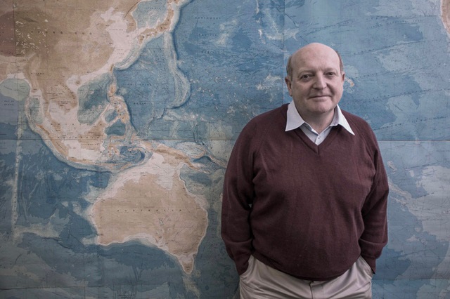 a man standing in front of a large rock