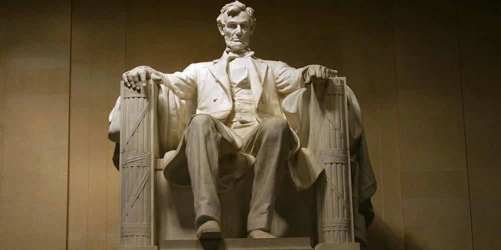 Abraham Lincoln standing in front of a mirror posing for the camera with Lincoln Memorial in the background