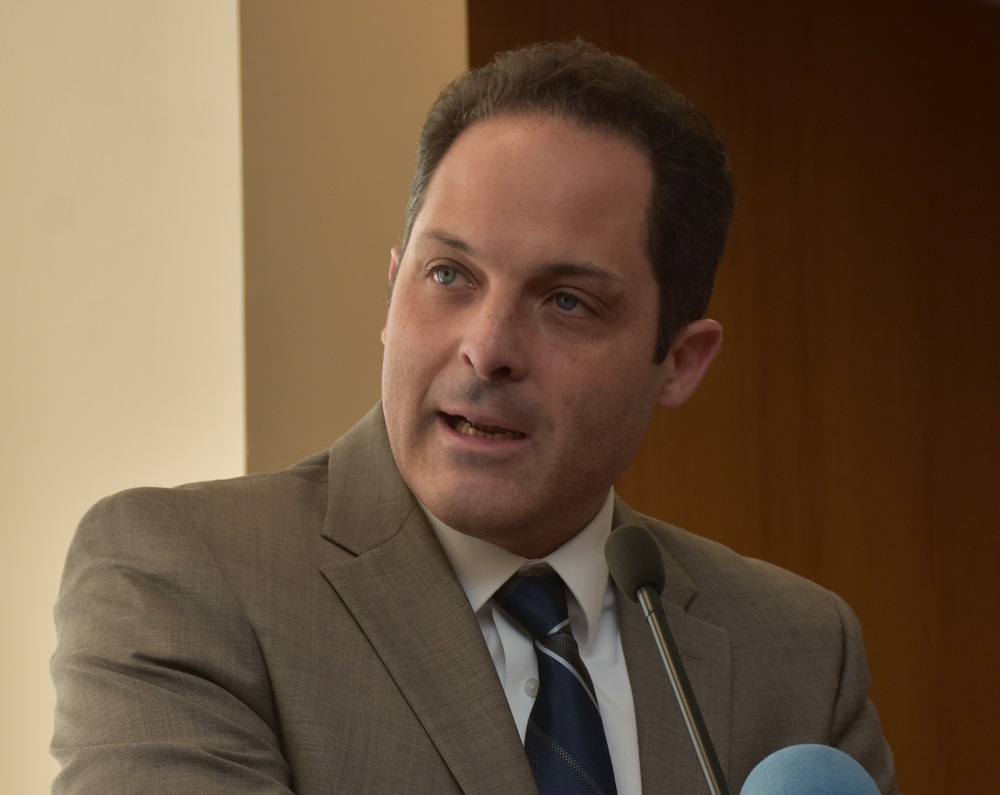 a man wearing a suit and tie smiling and looking at the camera