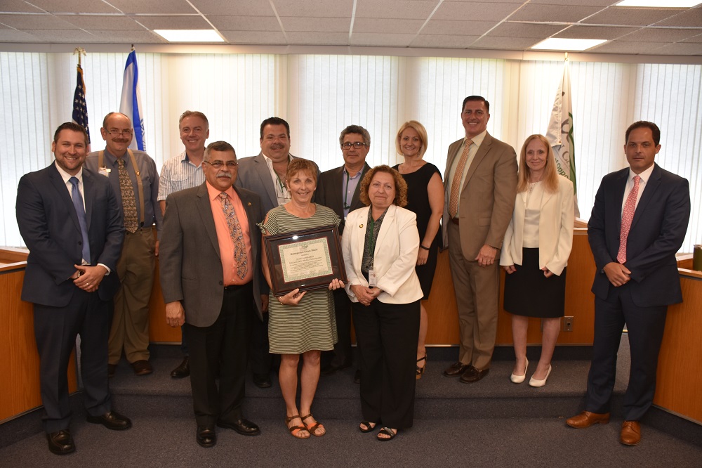 June Lombardi holding her award with legislators