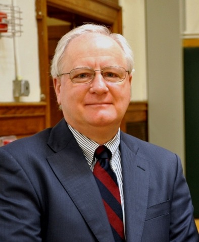 a man wearing a suit and tie smiling at the camera